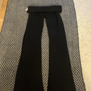 Svarta vida kostymbyxor - Säljer ett par svarta kostymbyxor med hög midja och vida ben. Byxorna har en klassisk look och passar perfekt till en stilren outfit. Materialet känns mjukt och följsamt, och modellen ger en snygg siluett.