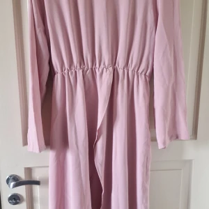 Ljusrosa långärmad klänning från SHEIN - Säljer en ljusrosa långärmad klänning från SHEIN i storlek XXL. Klänningen har resår i midjan och är tillverkad i ett mjukt, lätt material. Perfekt för dig som gillar enkel och stilren design.