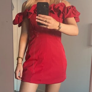 Röd axelbandslös mini klänning - Snygg röd axelbandslös klänning med volangdetaljer upptill. Klänningen har en figurnära passform som framhäver silhuetten.🌹