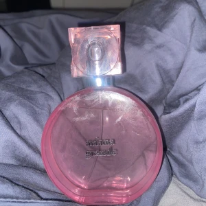 Ariana Grande parfym, rosa hjärtformad flaska - Säljer en Ariana Grande Thank you next parfym i en unik hjärtformad flaska med ljusrosa detaljer och genomskinligt rosa lock. Flaskan rymmer 100 ml och har en modern, feminin design med metallisk dekor framtill.