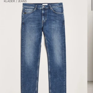 Blå jeans från Tiger of Sweden - Snygga blå jeans från Tiger of Sweden i storlek 30/32 med klassisk femficksdesign och raka ben. Jeansen har en ljus tvätt och läderpatch med logga bak i midjan. Perfekta för en stilren och avslappnad look. Nypris runt 1599kr.