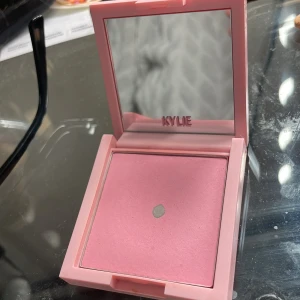 Kylie Cosmetics Pressed Blush Powder 'Winter Kissed' - Rosa puderrouge från Kylie Cosmetics i nyansen 'Winter Kissed'. Kommer i en fyrkantig ljusrosa dosa med spegel i locket. Perfekt för att ge kinderna en fräsch och naturlig färg.