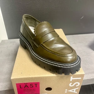 Olivgröna loafers från LÄST med chunky sula - Säljer ett par oanvända olivgröna loafers från LÄST med kraftig, svart platt sula. Skorna är i äkta skinn. Nypris 2800 kr!