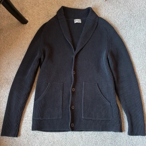 Cardigan  - Säljer denna väldigt snygga cardigan från J.Lindeberg i storlek L men sitter som en M. Extremt fint skick i den fina färgen marinblå, till ett väldigt bra pris 399kr