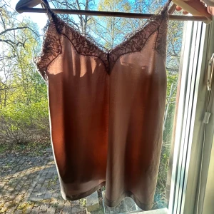 Gammel rosa linnetopp med spets - Säljer en gammel rosa linnetopp med vacker spetsdetalj längs v-ringningen. Tunt och lätt material, perfekt för varma dagar eller som lager under en tröja. Snygg och enkel att matcha till olika outfits.