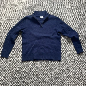 Marinblå half zip från These Glory Days - Säljer en marinblå stickad tröja från These Glory Days. Tröjan har halv dragkedja vid kragen. Tröjan är av 100% Marion ull.