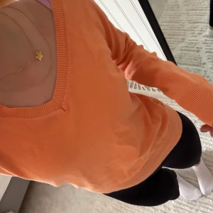 Orange v-ringad tröja från Lindex - Säljer en orange v-ringad tröja från Lindex i mjukt material. Tröjan har långa ärmar och ribbade muddar vid ärmslut och nederkant. Perfekt för lager-på-lager och enkel att matcha med olika outfits.