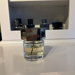Yves Saint Laurent L'Homme - L'Homme från Yves Saint Laurent är en elegant herrparfym i en rund glasflaska med silverfärgat, sexkantigt lock. Doften är fräsch och maskulin, perfekt för dig som gillar stilrena och klassiska parfymer.