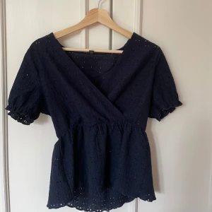 Mörkblå omlottblus  - Säljer en mörkblå omlottblus med puffärmar. Använd ett fåtal gånger.