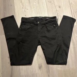 Svarta Replay Anbass Jeans  - Säljer ett par svarta Replay Anbass jeans med klassisk och bra passform. Byxorna har dragkedjegylf och diskret Replay-logga vid fickan. Perfekta för dig som gillar stilrena och bekväma jeans.