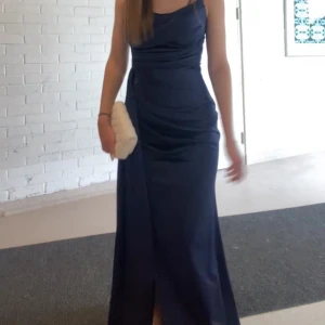 Balklänning  - Elegant mörkblå klänning som passar perfekt till speciella tillfällen, tex balen. Klänningen har en slits framtill som ger en wow känsla.