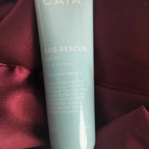 SOS Rescue Balm - En ljusblå tub med SOS Rescue Balm från CATA, passar alla hudtyper. Innehåller sheasmör och vitamin E som återfuktar och mjukgör huden. Perfekt för torra partier och ger näring med en krämig konsistens.