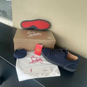 Mörkblå sneakers från Christian Louboutin - Säljer ett par mörkblå sneakers från Christian Louboutin med klassisk röd sula. Skorna är använd bara tre gånger Annas e helt ny säljer på grund av fel storlek på mig!