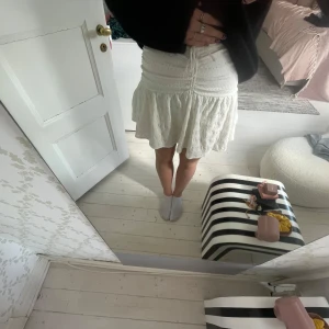 Vit minikjol  - Supersöt vit kjol från Bershka med volang och knytning framtill. Kjolen är kort och har en lätt utsvängd form som ger en luftig känsla. Perfekt för dig som gillar en feminin och trendig stil.