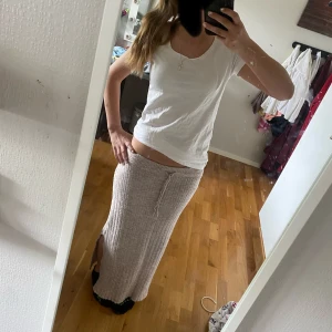 Beige ribbad långkjol från 157 - Säljer en beige ribbad långkjol från 157. Kjolen har en rak passform med resår i midjan och knytband. Perfekt för dig som gillar en enkel och stilren look. Kjolen är mjuk och skön, passar till många olika outfits.