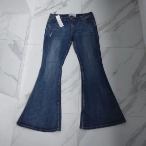 Bootcut lågmidjade jeans - Utsvängda lågmidjade jeans med mindre slitningar! Aldrig använd, lappen kvar. Mått: Total längd 107 cm Innersöm 80 cm Midjevidd 44 cm x 2 Lårvidd 29 cm x 2 Benvidd längst ner 36 cm x 2 Höjd från gren och upp 25 cm