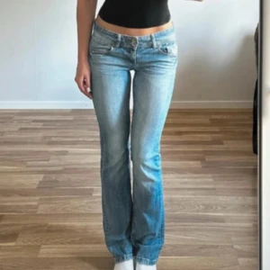 Ljusblå bootcut jeans med broderade fickor - Snygga ljusblå jeans med bootcut passform och låg midja. Jeansen har klassiska fem fickor och coola broderade detaljer på bakfickorna. Tillverkade i mjukt denim med lätt slitning för en avslappnad vibe.