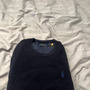 Mörkblå stickad tröja Polo Ralph Lauren - Snygg mörkblå stickad tröja från Polo Ralph Lauren med klassisk rund halsringning och diskret broderad logga på bröstet. Perfekt för dig som gillar stilrena och tidlösa plagg. Långärmad och i mjukt material som känns skönt mot huden. Storlek: SP. Tröjan är i fint skick är köpt ny hos care of carl! Mvh 