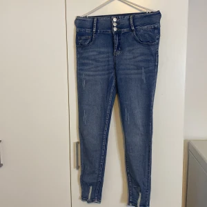 Blå skinny jeans från SHEIN, M - Snygga blå skinny jeans från SHEIN med hög midja och tre knappar framtill. Jeansen har slitna detaljer, klassiska fickor och smal passform hela vägen ner. Perfekta för dig som gillar en tajt look och vill ha ett par stilrena jeans i garderoben.