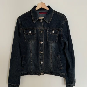 Jeansjacka från Malinuo Jeans - Klassisk jeansjacka från Malinuo Jeans med snygga kontrastsömmar och  metallknappar. Jackan har två bröstfickor med lock, två sidofickor och en rak passform.