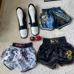 Thaiboxningsshorts o skydd - Säljer 3 st thaiboxningsshorts i  storlek L. Använda en gång och tvättade.  250kr/st Alla 3 = 600kr  Venum lindor 4m. Använda en gång och tvättade. Nypris = 99kr  Säljer för 50kr  Benskydd från ”be like water” i storlek L. Använda i ett halv år och tagit hand om dem bra och alltid luftat dem.  Nypris = 800kr Säljer för 400kr  (Allt är unisex)