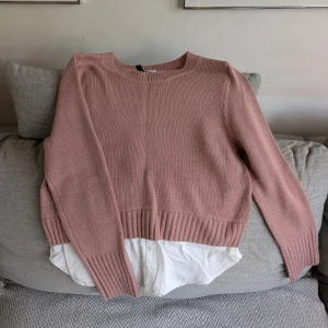 Rosa stickad tröja med skjortdetalj från Divided - Stickad tröja i dammigt rosa från Divided H&M. Tröjan har en insydd vit skjortdetalj nedtill som ger en lager-på-lager-look. Jag är ca 170 cm för referens. Vid köp av flera klädesplagg av mig samfraktar jag såklart!