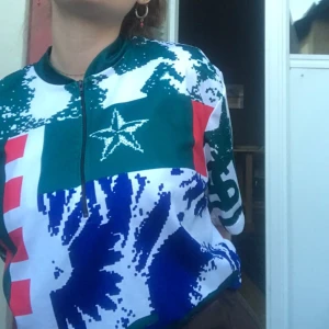 Uvex bikestyle cykeltröja med mönster - Fet cykeltröja från Uvex bikestyle med digitalt inspirerat mönster i grönt, blått, vitt och rött. Halv dragkedja framtill, korta ärmar och cool stjärndetalj på bröstet. 