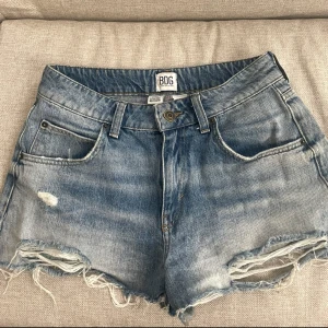 BDG ljusblå jeansshorts - Snygga och slutsålda ljusblå jeansshorts från BDG med slitna detaljer och fransig nederkant. Klassisk femficksmodell med knapp och dragkedja framtill. Perfekta för sommaren och ger en avslappnad vibe. 