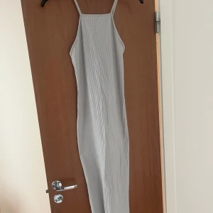 Ljusgrå ribbad långklänning Gina Tricot - Supersnygg ljusgrå långklänning från Gina Tricot med ribbad struktur och smala axelband som korsas i ryggen. Klänningen är oanvänd o prislapp finns kvar