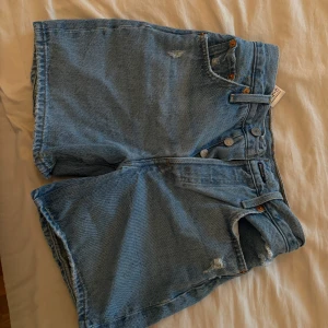Levi's ljusblå jeansshorts W23 - Snygga ljusblå jeansshorts från Levi's med klassisk femficksdesign, hög midja och råa kanter. 