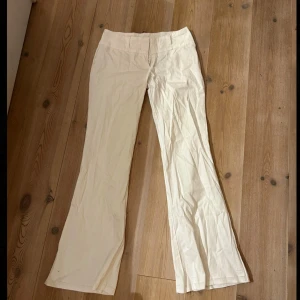 Vita kostymbyxor med diskreta ränder - Snygga vita kostymbyxor med subtila vertikala ränder, utan fickor, lågmidjade och utsvängd bootcut-stil. 