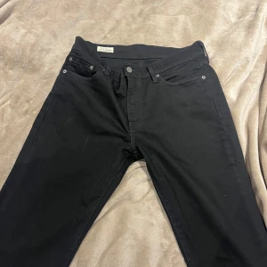 Svarta Levi's 511 jeans W30 L30 - Säljer ett par svarta Levi's 511 jeans. Jeansen har normal passform, raka ben och är tillverkade i bomull med en liten stretch. Snygga svarta sömmar och Levi's ikoniska röda etikett bak på fickan. Använda en gång inga defekter, köpta för 1000kr mitt pris 225kr