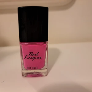KICKS Electric Sky nagellack rosa - Nagellack från KICKS i färgen Electric Sky, en intensiv och poppig rosa nyans. Kommer i en stilren, fyrkantig glasflaska med svart lock. Perfekt för dig som vill ha färgstarka naglar med glansig finish. Innehåller 10 ml.