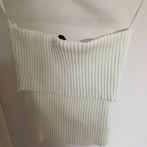 Vit ribbad bandeau topp från H&M - Supersnygg vit bandeau topp från H&M i ribbstickat material. Toppen är ärmlös och har en croppad passform som sitter tight. Perfekt till sommarens alla outfits och enkel att styla med både jeans och kjol.