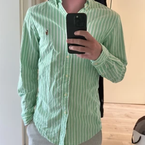 Grön- och vitrandig skjorta Ralph Lauren - Snygg grön skjorta med vita ränder från Ralph Lauren. Perfekt för dig som gillar stilrena och fräscha plagg. Pris inte satt i sten👍