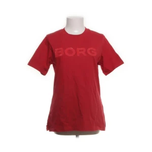 Röd t-shirt från Björn Borg - Röd t-shirt från Björn Borg med stort glansigt BORG-tryck på bröstet. Har slits på sidorna! Köpt från Sellpy i nyskick med lappen kvar och aldrig använd av mig heller! 💕