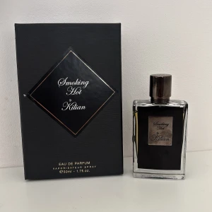 Kilian Smoking Hot Eau de Parfum 50ml - Exklusiv parfym från Kilian, Smoking Hot, i elegant svart glasflaska med silverdetaljer och matchande svart kartong. Flaskan rymmer 50ml och har en lyxig metallkork med ingraverad logga. Perfekt för dig som gillar unika och sofistikerade dofter.
