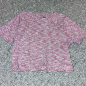 Stickad croppad topp - Superfin croppad topp i rosa och vitt med korta ärmar. Toppen är stickad och gjord i mjukt material som känns skönt mot huden. Perfekt för dig som gillar en avslappnad men ändå söt stil.
