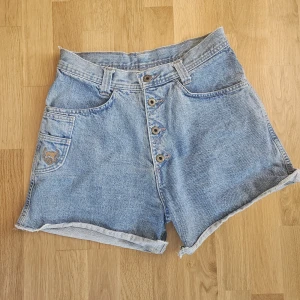 Vintage santana jeansshorts  - Säljer dessa snygga och tidlösa jeansshorts från det kanadensiska märket Santana. Dessa shorts är i mycket bra skick och redo för en ny ägare Detaljer: * Märke: Santana (PAR BY PARASUCO), tillverkade Kanada. * Färg: Klassisk ljusblå denimtvätt, lätt att matcha med det mesta i garderoben. * Storlek: S (Small). För bästa passform, se de uppmätta måtten nedan. * Skick: Mycket bra skick! Inga anmärkningar, ser knappt använda ut. Mått (platt liggande): * Midja: ca 36 cm * Höft: ca 49 cm