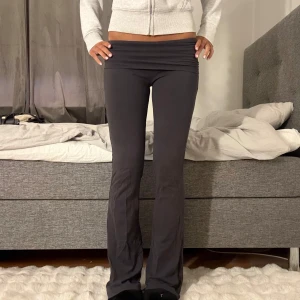 Yogapants - Svarta/grå mjukisbyxor med låg midja och bootcut-snitt. Byxorna är i mjukt material och har en enkel, stilren look som passar perfekt till en avslappnad outfit.