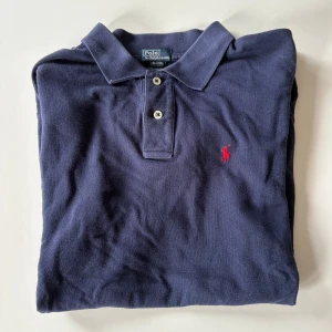 Marinblå pikétröja från Ralph Lauren - Klassisk marinblå pikétröja från Ralph Lauren. Står den är xl men är en mindre passform mer som m eller l.