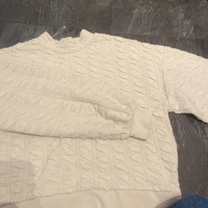 Vit quiltad tröja från Pieces - Säljer en vit quiltad tröja från Pieces i storlek S. Tröjan har ett unikt strukturerat mönster, rund halsringning och långa ärmar med muddar. Perfekt för dig som gillar en stilren men ändå cool look.