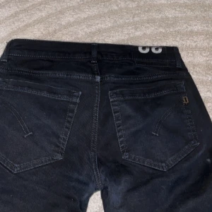 Svarta Dondup jeans ”GEORGE” modellen - Säljer ett par svarta skinny jeans från Dondup med klassisk femficksdesign och diskret D-detalj på bakfickan. Jeansen har smal passform och är tillverkade i stretchigt bomullsmaterial för en bekväm känsla. Perfekta för dig som gillar en clean och stilren look. Den eftertraktade ”GEORGE” modellen i storlek 32😊 hör av er vid minsta fundering!
