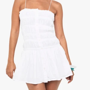 Vit kort klänning - Supersöt vit kort klänning med smala axelband och knappar. Aldrig använd med prislapp kvar!! Säljer då den tyvärr var för liten på mig😢