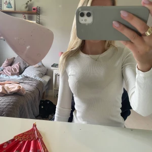 Vit ribbad långärmad tröja  - Säljer en vit långärmad tröja från Gina Tricot, basically basics-kollektionen. Tröjan är ribbad och har en tight passform med rund halsringning. Perfekt att styla med jeans eller kjol för en clean och enkel look.