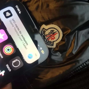 Svart Moncler pufferjacka med huva - Säljer en svart pufferjacka från Moncler med stickade ärmar och huva. Jackan har glansig quiltad front, dragkedja och en snygg ficka med Moncler-logga på ärmen. Pris kan diskuteras