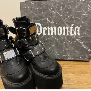 Demonia svarta platåboots med spännen - Riktigt feta svarta Demonia platåboots . Med originalkartong. Storlek 36.