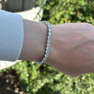 Silverfärgat tennisarmband med stenar - Ett stilrent tennisarmband i silverfärg med gnistrande, runda stenar längs hela bandet. Armbandet har en klassisk och elegant design med säker låsning. Perfekt för dig som gillar att sticka ut med lite extra bling på handleden.