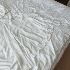 Vit blus med v-ringning från KappAhl - Säljer en stilren vit blus från KappAhl i storlek 34. Blusen har v-ringning, långa ärmar och dubbla lager tyg som ger en flowy känsla. Perfekt för dig som gillar en clean och fräsch look. Materialet känns lätt och luftigt.