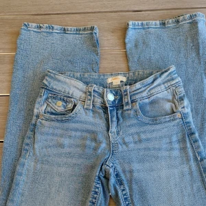 Ljusblå jeans från Gina Tricot, stl 152 - Snygga ljusblå jeans från Gina Tricot i klassisk femficksmodell. Jeansen har låg midja och bootcut.